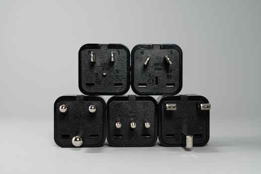 A collection of various black international power plug adapters for global electronics use.